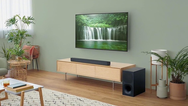 The Sony HT-S400 set up on a TV stand. The wireless subwoofer is placed to the right of the stand, and a TV is mounted above the soundbar.