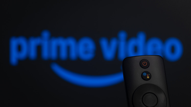 smart tv remote in foreground, blurry prime video logo in background