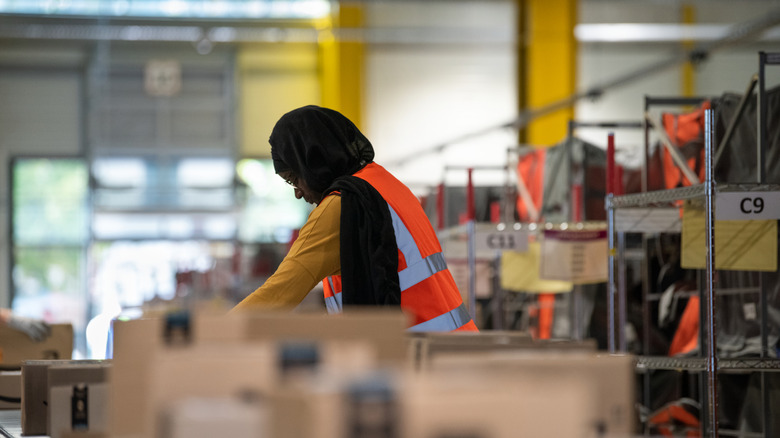 Amazon warehouse worker managing items on a conveyor.
