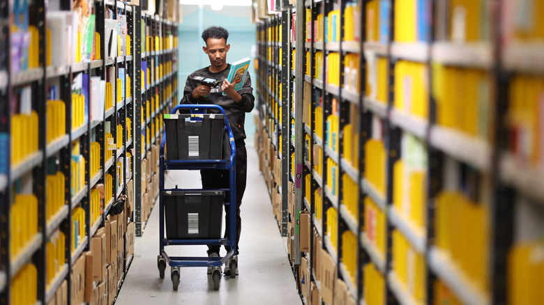 Amazon worker next to yellow plastic boxes inside a warehouse.