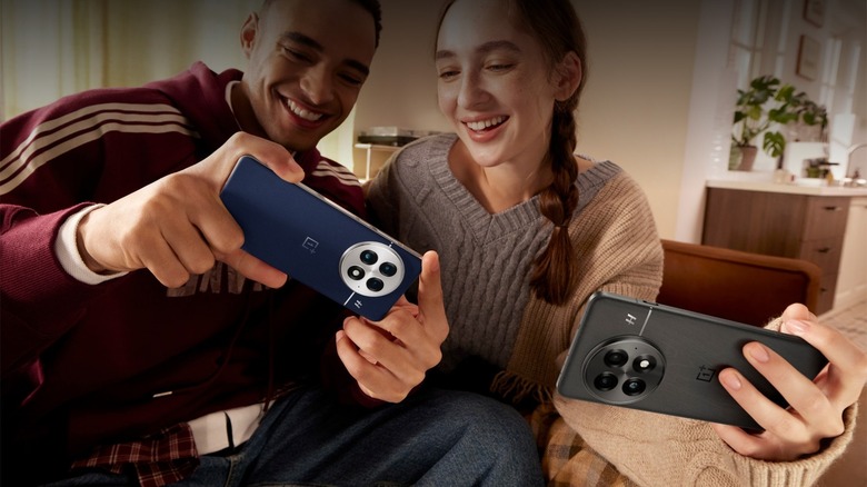 Man and woman using OnePlus 13 phones while laughing