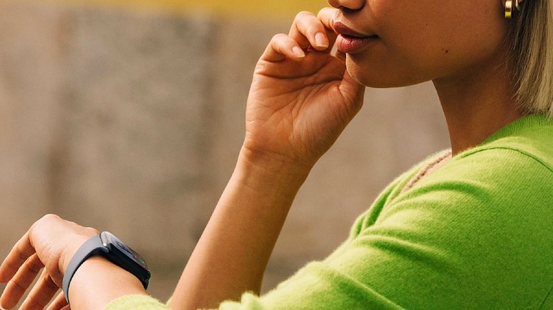 Apple Watch SE 3 worn on woman's wrist while listening to music.