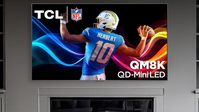 TCL 75-inch Class QM8K Series with football player onscreen mounted in living room.