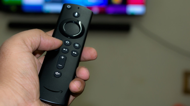 A hand holding an Amazon Fire TV Stick remote