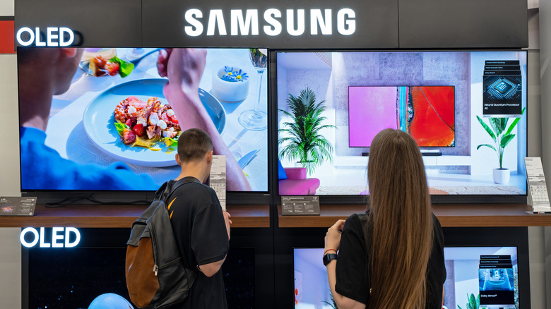A man and a woman browsing various Samsung OLED TVs