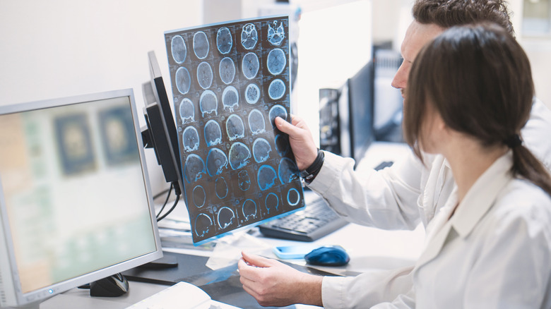 two doctors examine images of a brain