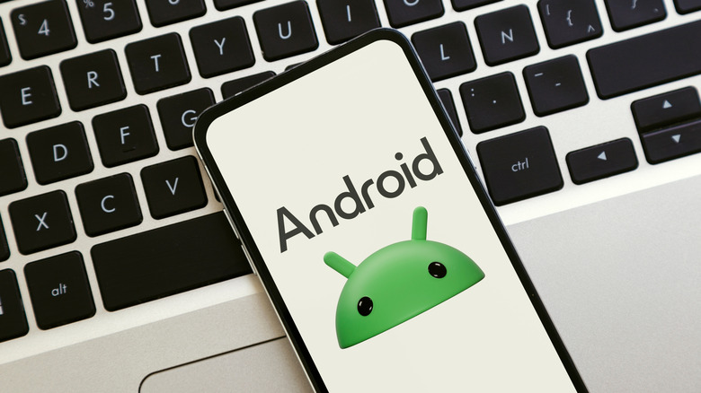 Android logo on phone screen resting atop a laptop keyboard