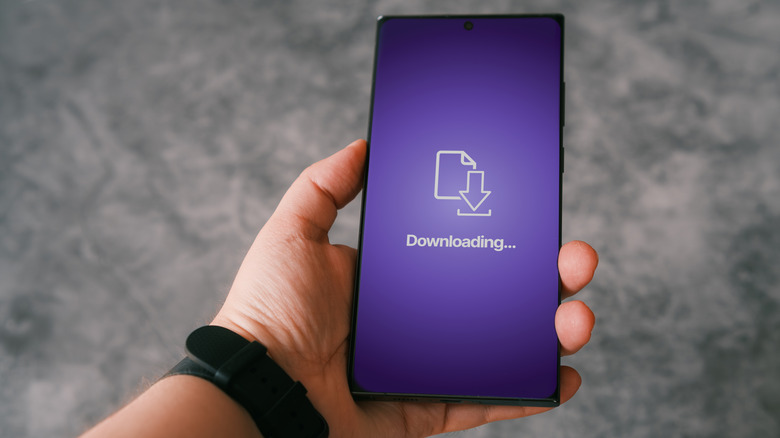 Person holding smartphone with concept of downloading app screen on display