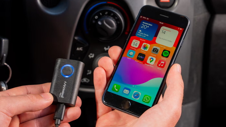 A person holding the AAWireless Two+ in one hand and a smartphone in the other.