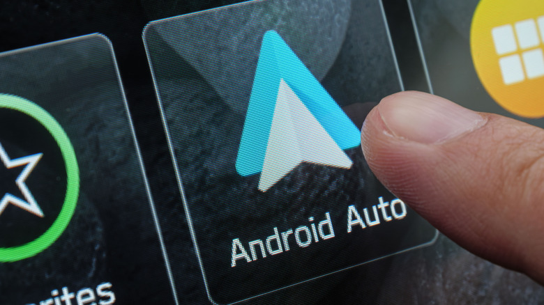 A finger is close to touching an Android Auto icon that appears on a touchscreen display