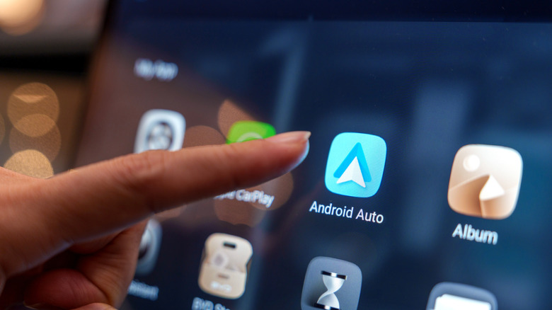 Someone's finger moving to launch android auto from car infotainment display.