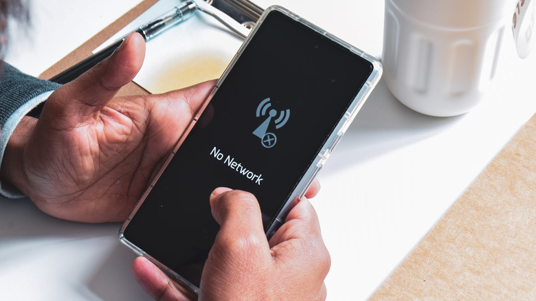 A person holding an Android phone with "no network" error