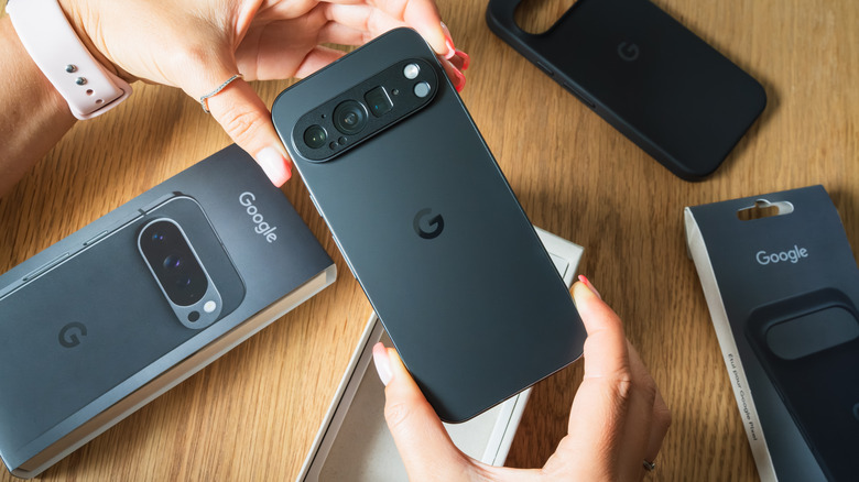 A pair of hands hold a new Google Pixel phone just after it was unboxed over a wooden table.