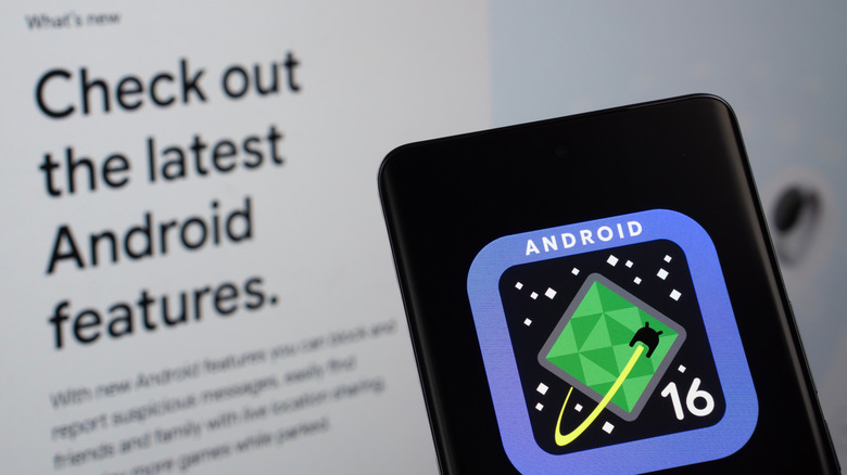 A phone displaying the Android 16 logo in front of a screen describing new Android features