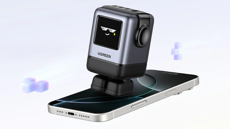 Ugreen's Uno Charger with a smile on its touch display, set on top of an iPhone