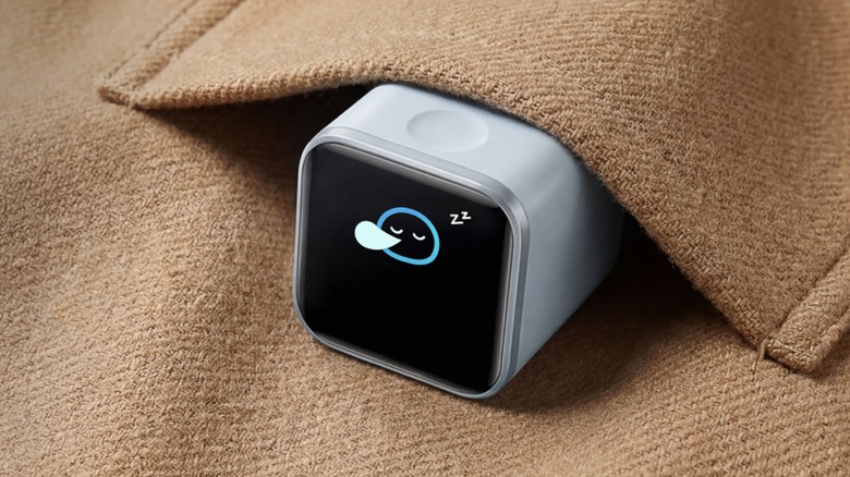 A promotional photo for the Anker Nano Charger, the white charger with a display showing a little cartoon circle taking a nap, the charger sits in the pocket of an article of clothing