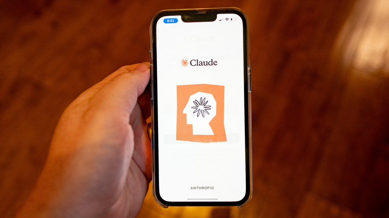 A person holding a smartphone showing Anthropic's Claude app on the screen.