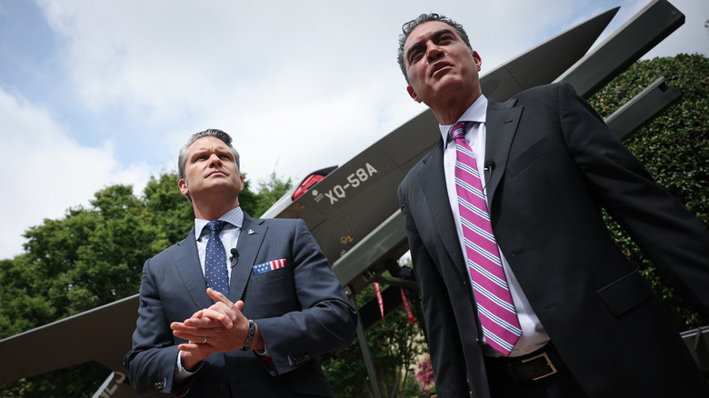 Pete Hegseth and DOD CTO Emil Michael stand beside a model fighter jet