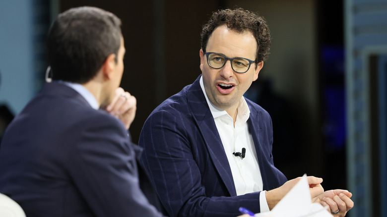 Dario Amodei smirks while speaking with an interviewer during a conference