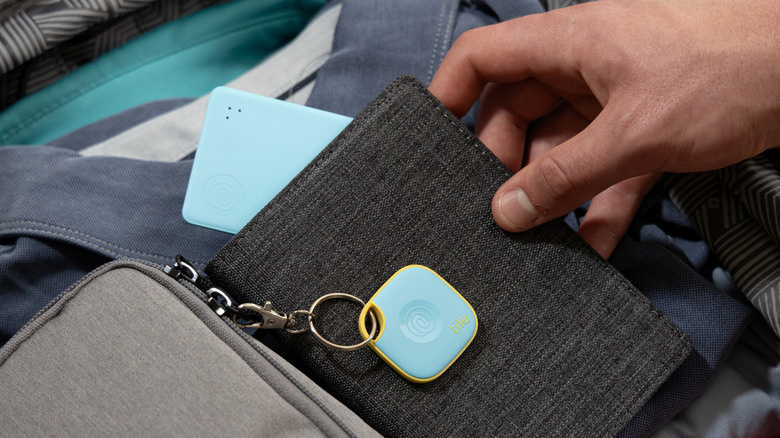 A person holding a wallet with Tile Slim tracker with a bag connected to Tile Mate tracker on the side