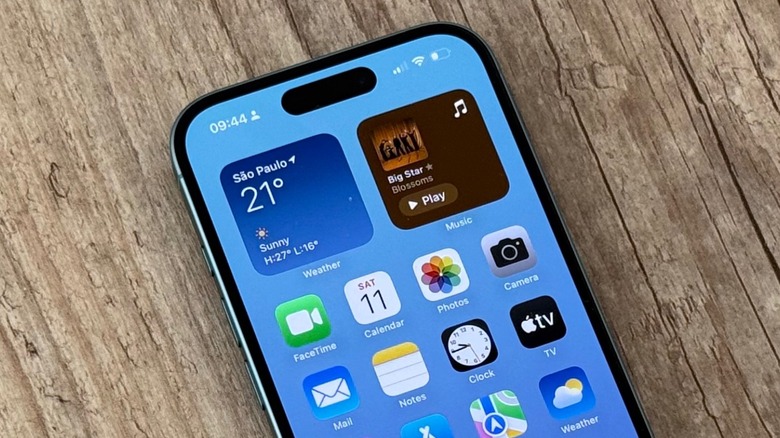 An iPhone 16 on a wooden table. It's running iOS 18.