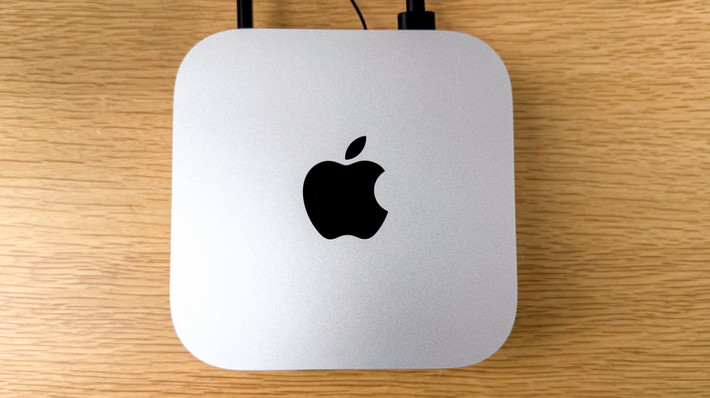 A silver M4 Mac mini sitting on a light-brown table