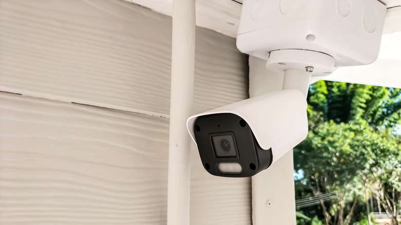 a white home security camera mounted outside a house