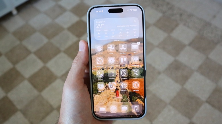 A hand holding an iPhone running iOS 26