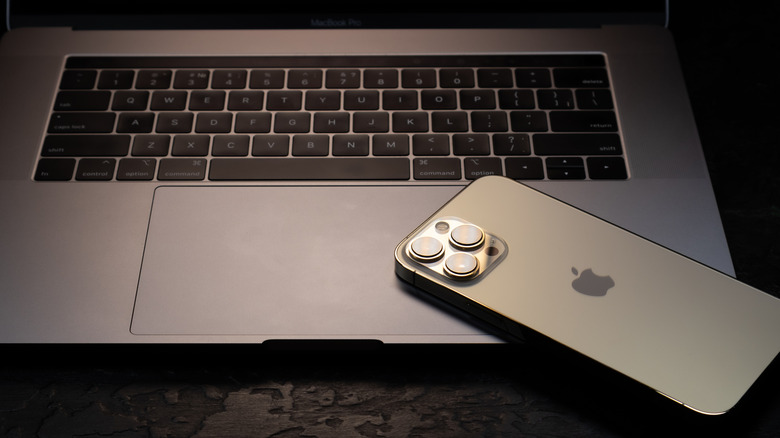 Modern smartphone Apple iPhone 15 Pro and Apple Macbook Pro laptop. Cupertino technology gadgetes. Brand logo name.