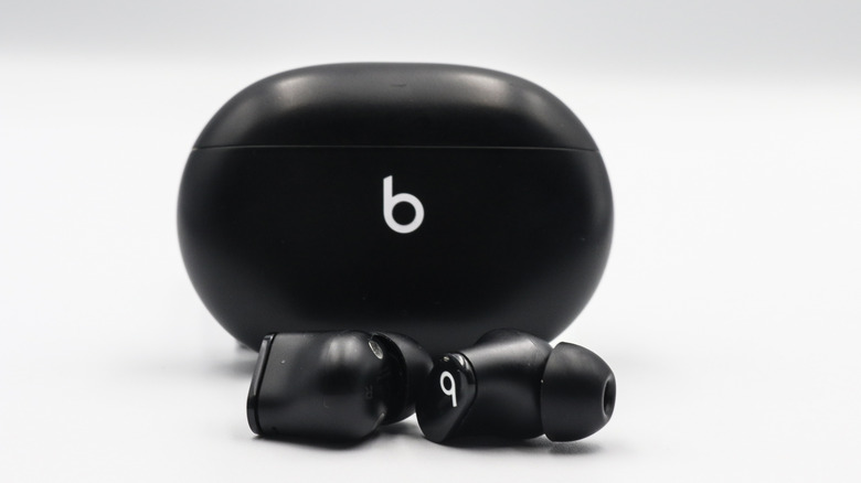 Beats Studio Buds in black with their case against a white-grey background