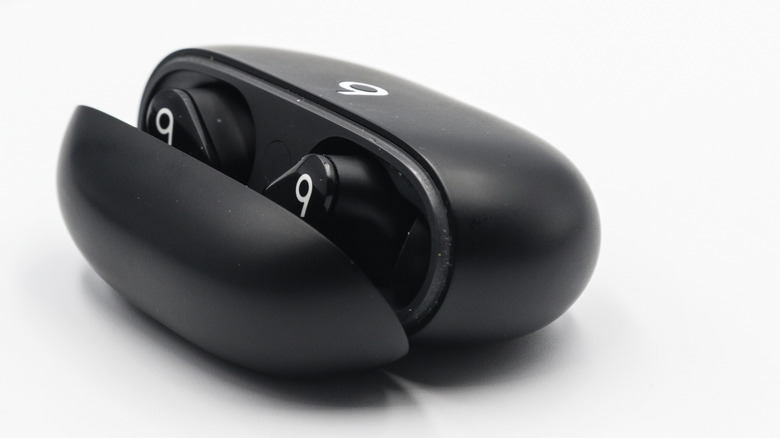 Beats Studio Buds in black laying flat on a grey surface