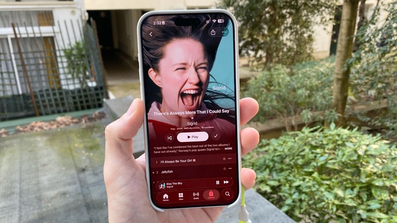 A hand holding an iPhone with an Apple Music album being displayed