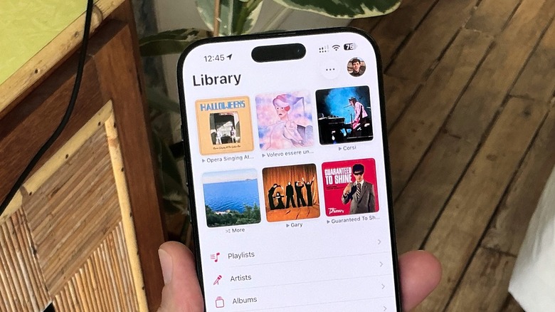 A man holding an iPhone with the Apple Music app opened up