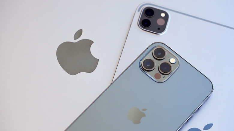 An iPhone, an iPad, and a closed MacBook atop one another