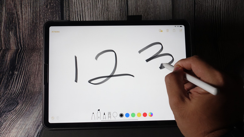 A person using an Apple Pencil on an iPad, drawing the numbers 1, 2, 3