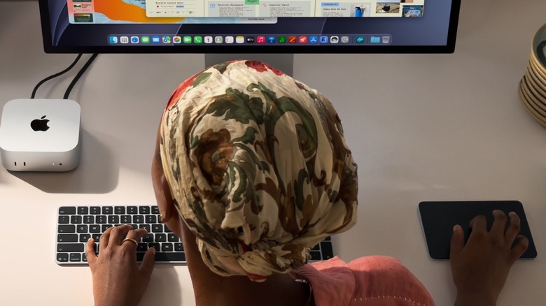 Person using the new M6 Mac mini on a desktop with a Studio Display and Magic Trackpad and Keyboard accessories