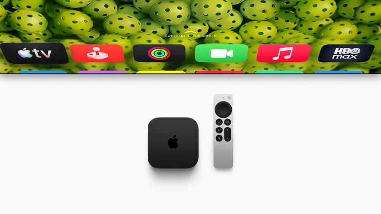 Apple TV 4K box and remote in front of a TV screen