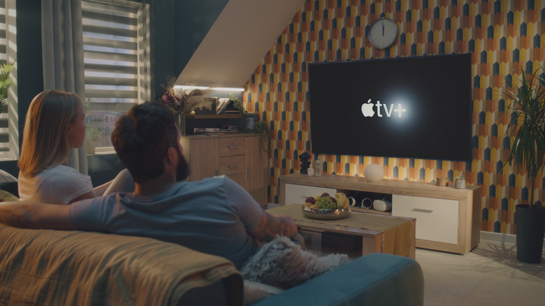 Apple TV+ playing on a TV with two people watching