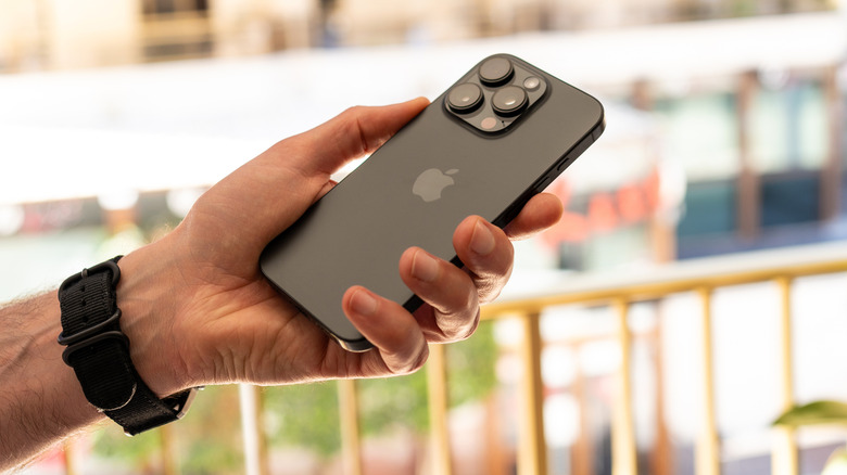 person wearing a watch holding an apple iphone 16 pro