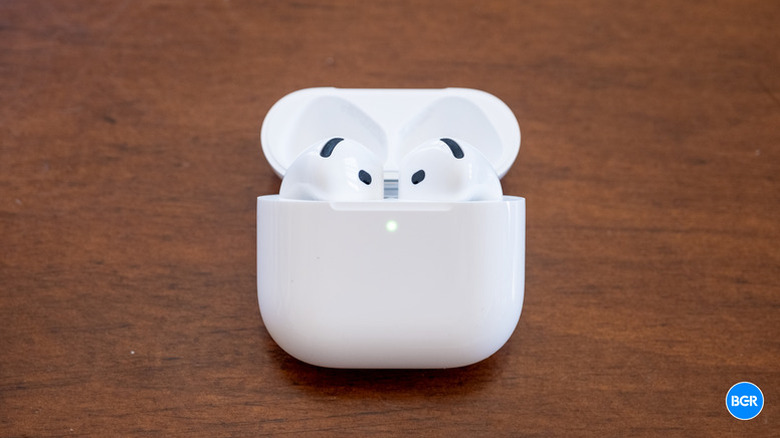 The AirPods 4 sitting in their white charging case on top of a wooden table