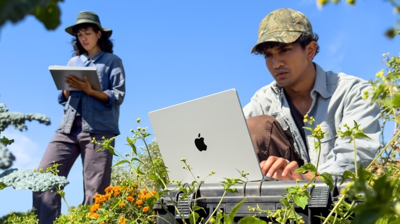 A man using a MacBook Pro on a field