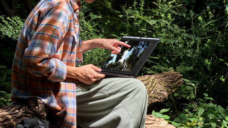 Man touching new touchscreen MacBook Pro with his finger