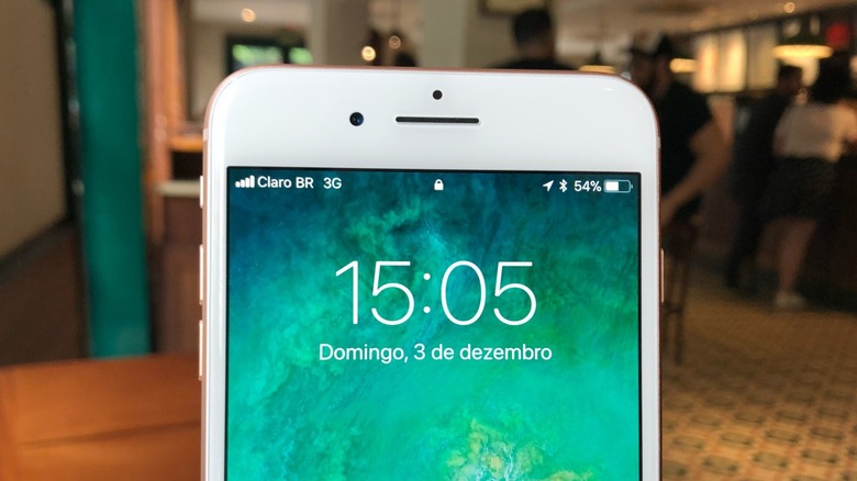 An iPhone 8 Home Screen with a Starbucks shop behind it.