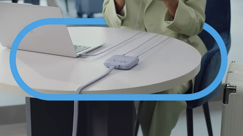 a small Anker charging station with two outlets on a workdesk
