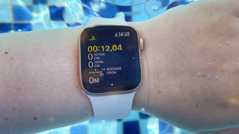A closeup of someone wearing a rose gold Apple Watch with a White band while submerged in water