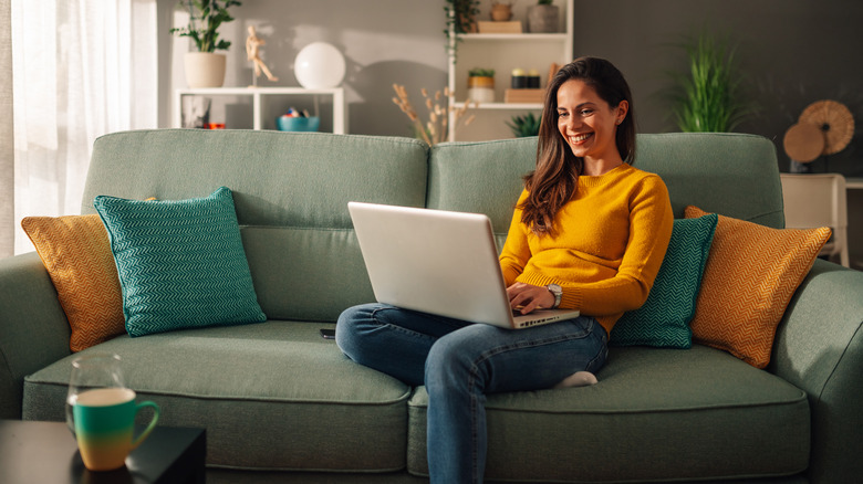 Woman sitting on the couch browsing the internet on her laptop
