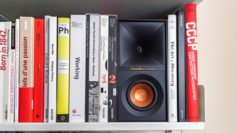 A Klipsch Reference bookshelf speaker placed on a literal book shelf.