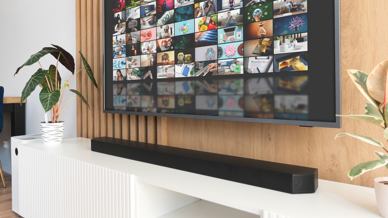 A soundbar placed below a wall-mounted TV.