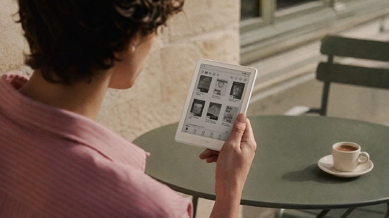 A person using a Boox Go 6 Gen II e-reader at an outdoor cafe.