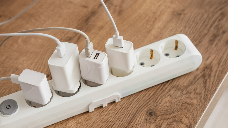 Three single-port USB adapters and another with two ports (but only one in use) plugged into a power strip.